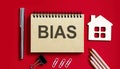 BIAS text written on a notebook with pencils and office tools and model wooden house Royalty Free Stock Photo