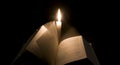 Bible book changes pages in front of a candle