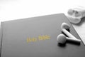 Bible and earphones on white table, closeup. Religious audiobook