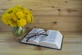 A Bible, glasses, a bunch of yellow dandelions on a wooden background. Warm tone. Royalty Free Stock Photo