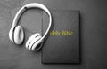 Bible and headphones on black, top view. Religious audiobook