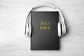 Bible and headphones on white background, top view. Religious audiobook