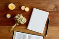 Bible with notebook, candlelight and flower over the wooden background.