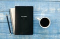 Bible, notebook and coffee cup on blue wooden background, flat lay.