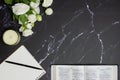 Bible and notebook with white roses over black marble background. Royalty Free Stock Photo