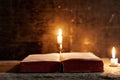 A bible open on a table next to a candle.