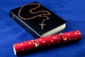 Bible with Rosary and Christmas Cracker on a Blue Cloth Background Royalty Free Stock Photo