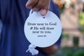 Bible verse quote - Draw near to God and He will draw near to you. James 4:8 with person showing text on white circle label paper.