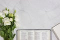 Bible with white roses over marble background with notebook. Royalty Free Stock Photo