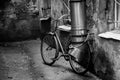 A bicycle attached to the drainpipe in the deadlock in black and white