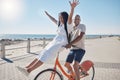 Bicycle, beach and couple with freedom, travel and summer holiday in city sidewalk for wellness, love and care in