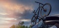 Bicycle on the car roof rack against sunset sky. copy space Royalty Free Stock Photo