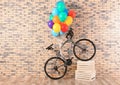 Bicycle with colorful balloons near brick wall