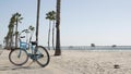 Bicycle cruiser bike by ocean beach, California coast USA. Summer cycle, lifeguard hut and palm tree