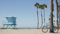 Bicycle cruiser bike by ocean beach, California coast USA. Summer cycle, lifeguard hut and palm tree Royalty Free Stock Photo