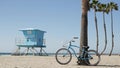 Bicycle cruiser bike by ocean beach, California coast USA. Summer cycle, lifeguard hut and palm tree Royalty Free Stock Photo