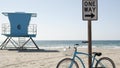 Bicycle cruiser bike by ocean beach, California coast USA. Summer cycle, lifeguard tower, road sign