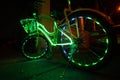 Bicycle decorated with the multicolored Christmas fairy neon lights at night time. closed up