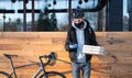 Bicycle delivery man in helmet holds a phone and pizza boxes.