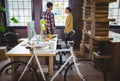 Bicycle by desk while coworkers discussing in background Royalty Free Stock Photo