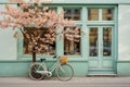 Bicycle with a flower basket parked by a light blue coffee shop cafe storefront window, with a pink blooming tree in Royalty Free Stock Photo