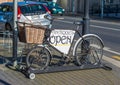 Bicycle with front basket is used to advertise an antique shop with parked Cars in the street Royalty Free Stock Photo