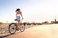 Bicycle fun on beach promenade. Happy woman riding bike on sunny summer boulevard. Seaside waterfront street for cycling.