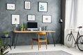 Bicycle in a grey home office interior with a wooden desk and ch Royalty Free Stock Photo