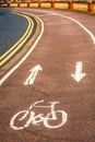 Bicycle icon painted in white paint on to a cycle path with two arrows that curls in the distance Royalty Free Stock Photo