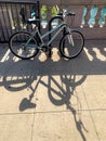 Bicycle and its shadow, as it leans against bike holder in Chicago Loop during summer