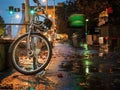 A bicycle left on night rainy city street