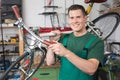 Bicycle mechanic carrying a bike in workshop smiling Royalty Free Stock Photo