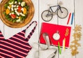 bicycle model, swimsuit, salad of fresh vegetables, red notepad, stopwatch and tape measure on a white wooden table Royalty Free Stock Photo