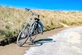 A bicycle parked along a coastal road with dunes at the background. Summer concept. Vacation. Bike rental. Biking. Tourism.