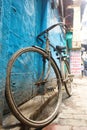 A bicycle parked on the blue wall in the alley of vanarasi .