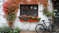 Bicycle parked beside hanging flower box on outside house wall.
