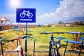 A bike rests beside a parking sign with a backdrop of grass and clouds