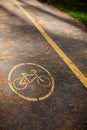 Bicycle path in the autumn park with yellow paint applied on the asphalt. The road for cyclists is covered with autumn leaves and Royalty Free Stock Photo