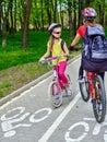 Bicycle path for child girls wearing helmet with rucksack ciclyng ride. Royalty Free Stock Photo