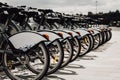 Bicycle rental service in the parking lot on the street. Row of bikes, focus on wheels.Take a bike and ride around the city Royalty Free Stock Photo