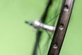 Bicycle repair workshop. On the hook hang new wheels. The hub is black and the spokes and rim are silver. The old bike here is