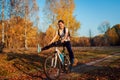 Bicycle ride workout in autumn park. Young woman biker riding a bike in fall forest having fun raising legs Royalty Free Stock Photo