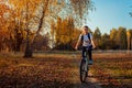 Bicycle ride workout in autumn park. Young woman biker riding a bike in fall forest. Healthy training Royalty Free Stock Photo