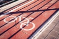 Bicycle sign on a red bike path under a shadow of a fence Royalty Free Stock Photo