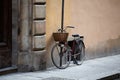 Bicycle standing near wall of ancient building. Female bike with wicker basket in front is fastened with chain to post Royalty Free Stock Photo