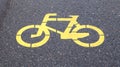 Bicycle symbol representing a path for bicycles. Yellow painted sign for bicycles on the asphalt. Flat lay, top view Royalty Free Stock Photo