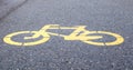 Bicycle symbol representing a path for bicycles. Yellow painted sign for bicycles on the asphalt. Flat lay, top view Royalty Free Stock Photo