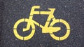 Bicycle symbol representing a path for bicycles. Yellow painted sign for bicycles on the asphalt. Flat lay, top view Royalty Free Stock Photo