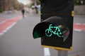 bicycle traffic light in yellow housing showing green while pedestrians crosses the way at european inner city intersection