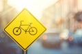 Bicycle warning sign on blur traffic road with colorful bokeh light abstract background Royalty Free Stock Photo